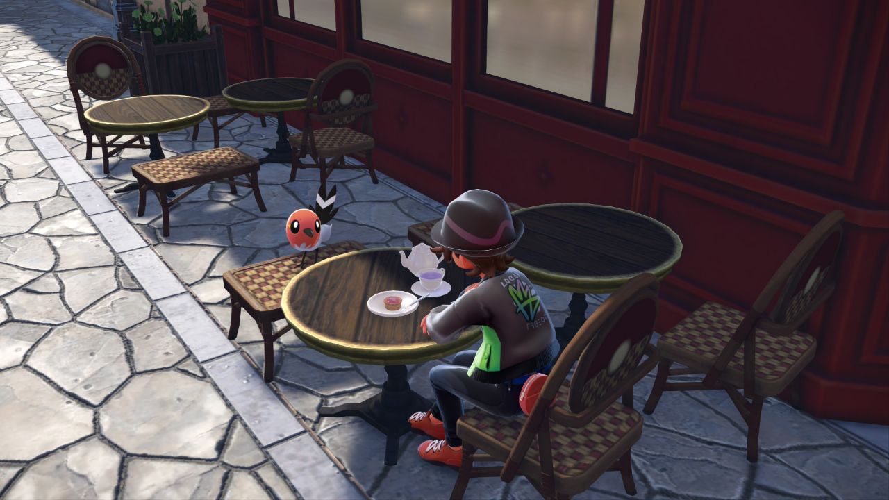 El prota en una terraza tomando un cafe con un fletching, un pajarillo que parece un petirrojo blanco y rojo con partes negras en la cola